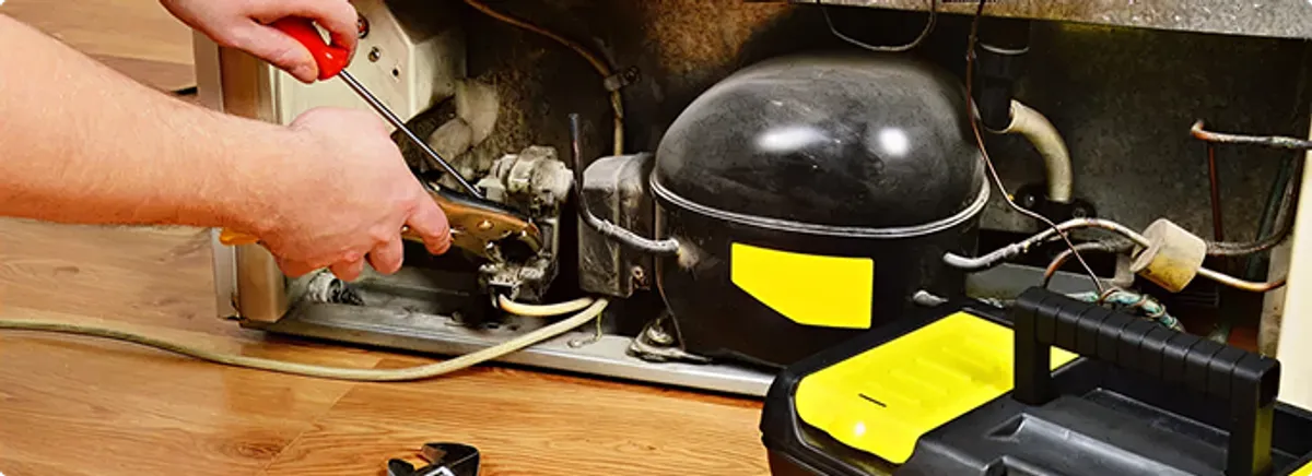 Refrigerator repair technician fixing the compressor and wiring in Auburndale, FL