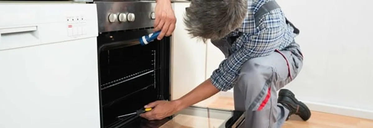 Oven repair technician inspecting and servicing an electric oven in Lakeland, FL